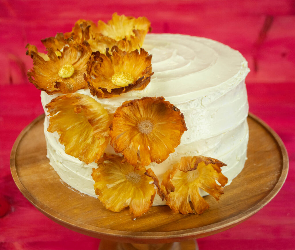 Piña Colada Dacquoise Cake on a wooden cake stand.