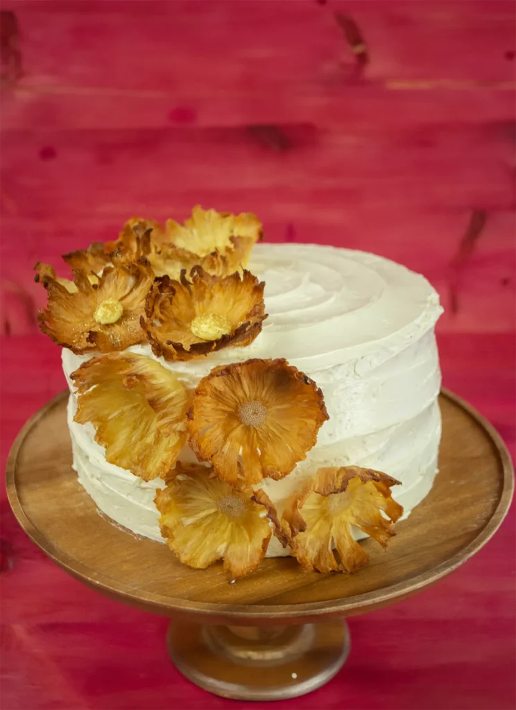 A Pina Colada Dacquoise cake on a wooden stand.