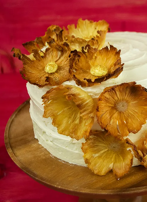 Pina Colada dacquoise cake decorated with pineapple flowers.