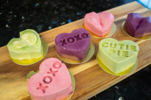 A selection of mini heart-shaped mousse cakes in matcha, blueberry, and raspberry flavours.