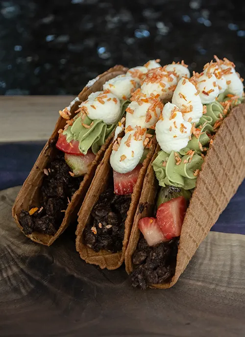 Three dessert tacos standing up side by side.