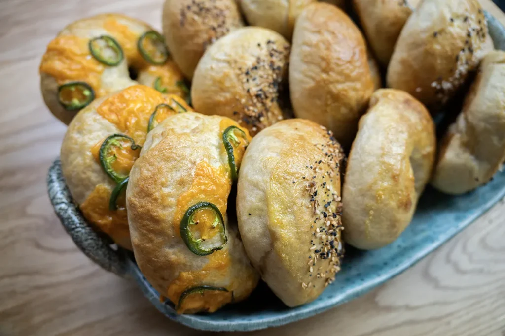 A variety of sourdough bagels on a ceramic tray.