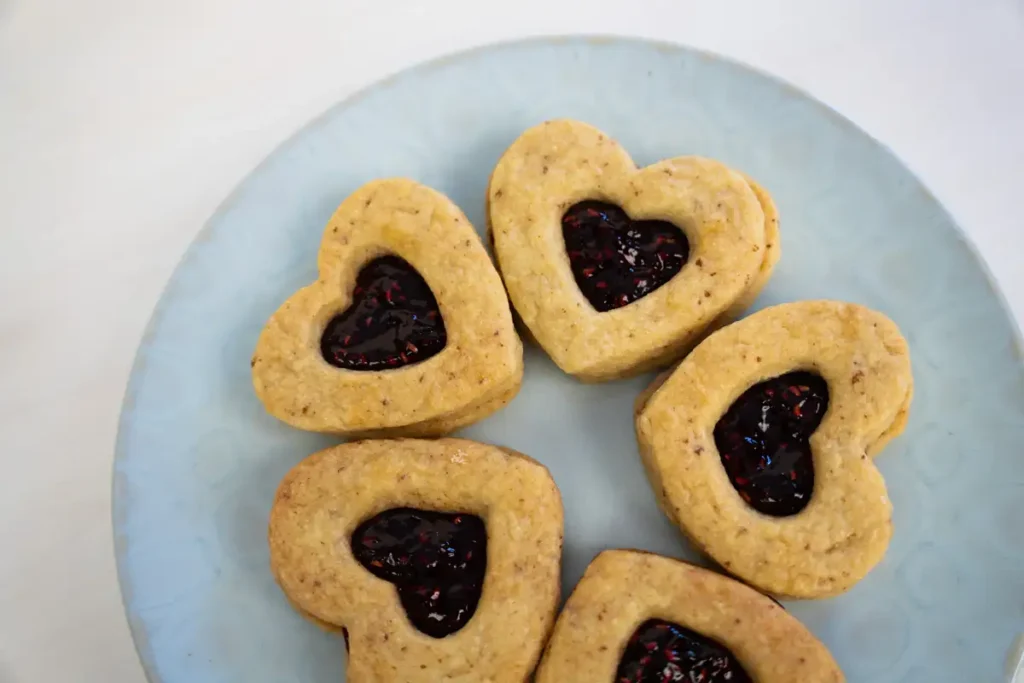 A plate of heart-shaped jam sandwich cookies arranged in a circle.