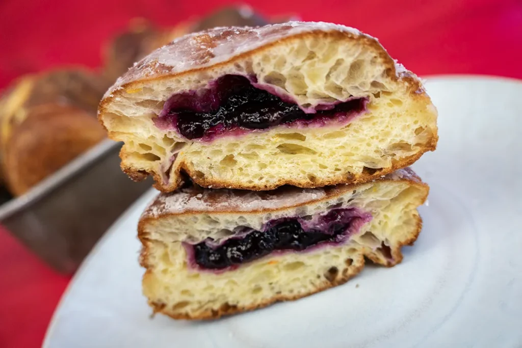 A paczek cut in half, showing its blueberry jam filling.