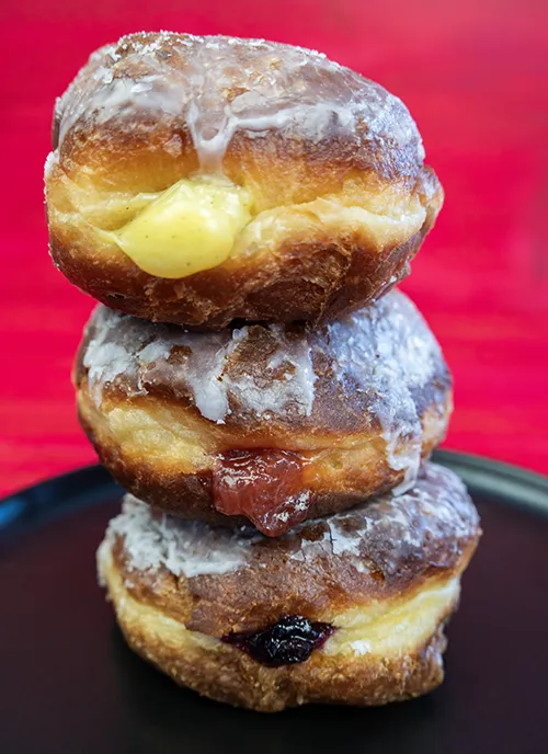 Stack of 3 paczki on a black plate.