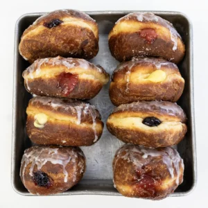Sourdough paczki lined up in a metal tin