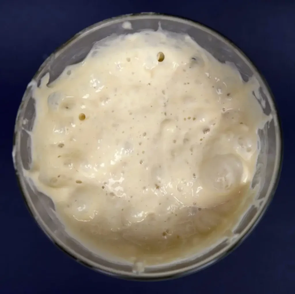 Top view of a jar of bubbly sourdough starter.