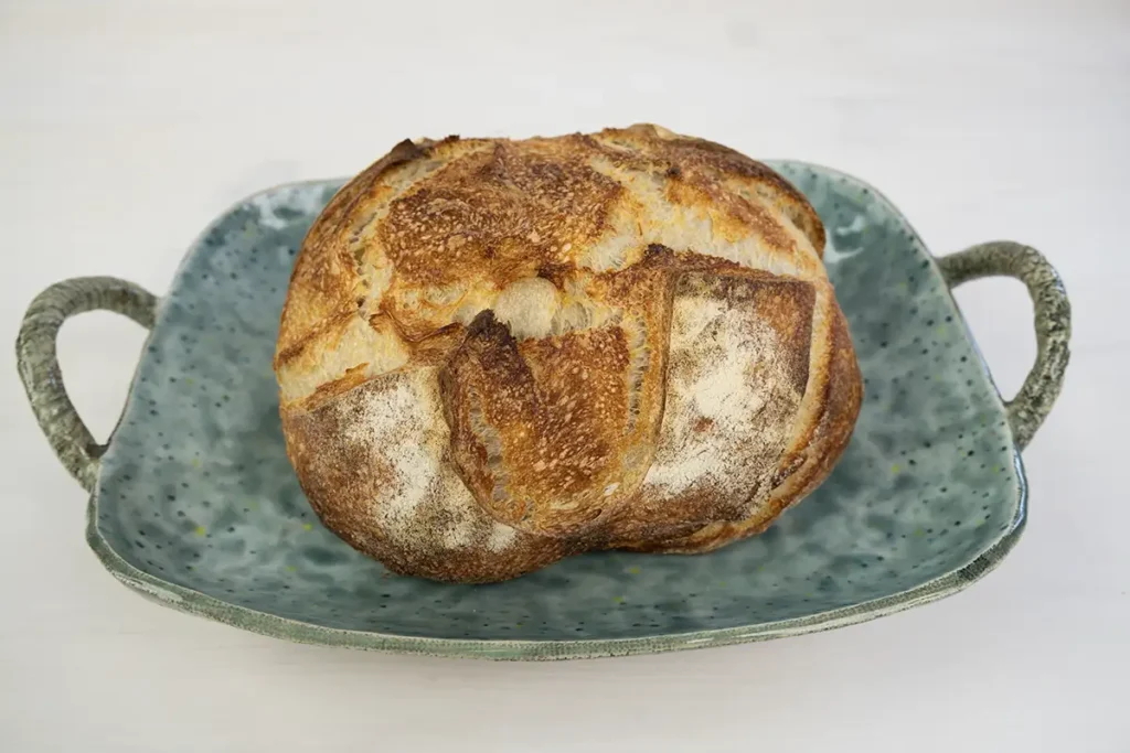 Loaf of sourdough bread on a blue ceramic plate.