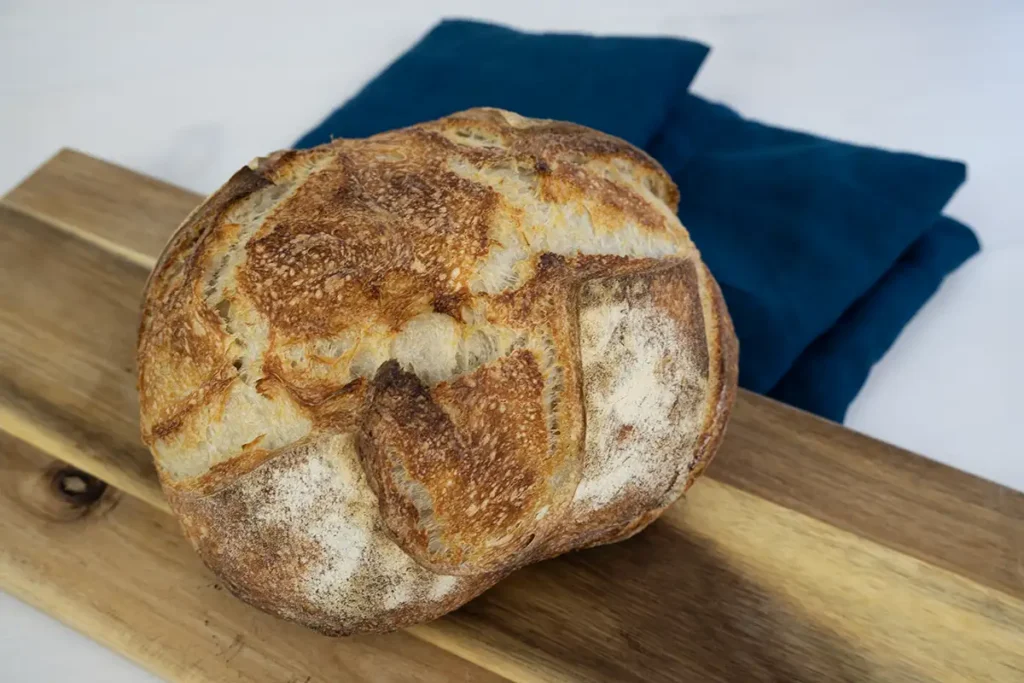 Loaf of baked bread on a wooden board.