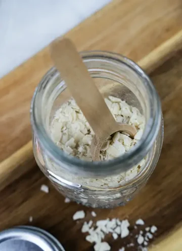 Top view of a small open mason jar with a wooden spoon and filled with dehydrated sourdough starter.