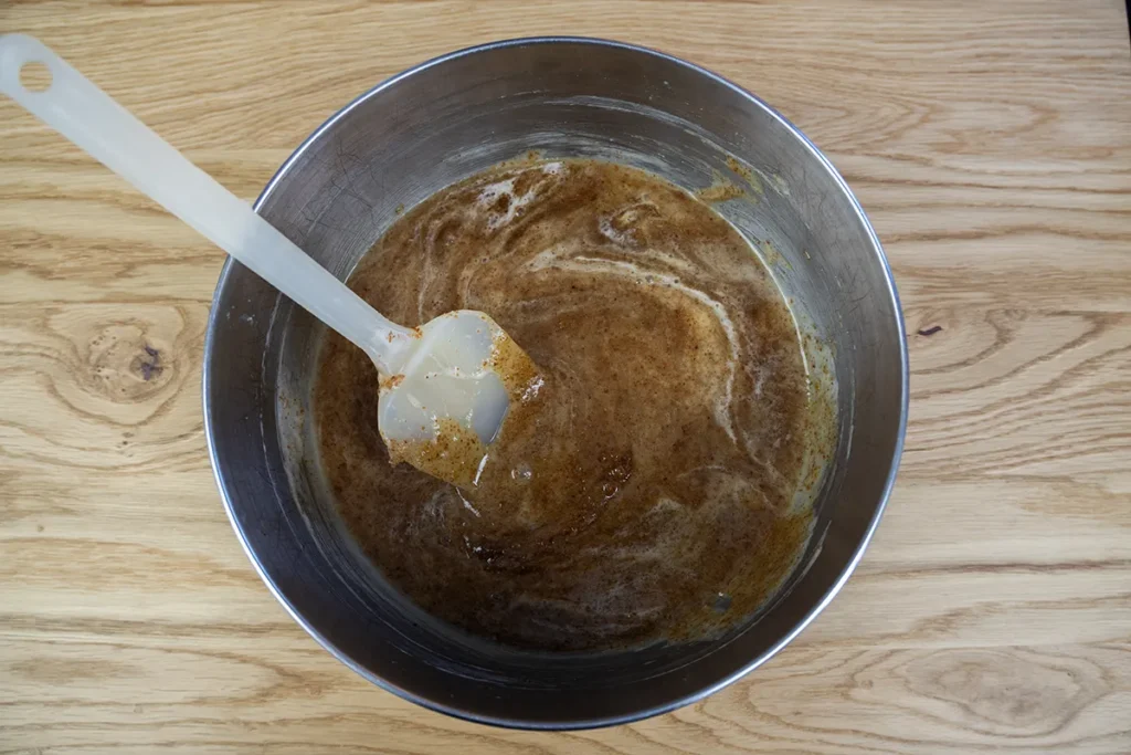 Adding white and brown sugar, sourdough starter, vanilla, and egg yolks to sourdough chocolate chip cookie dough.