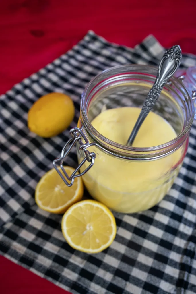 Top view of lemon curd in a glass jar with a spoon.
