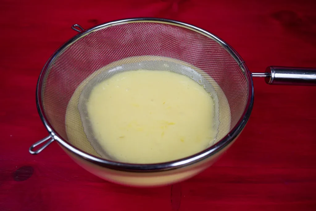 Step 4 of making lemon curd: pass the curd through a fine sieve.