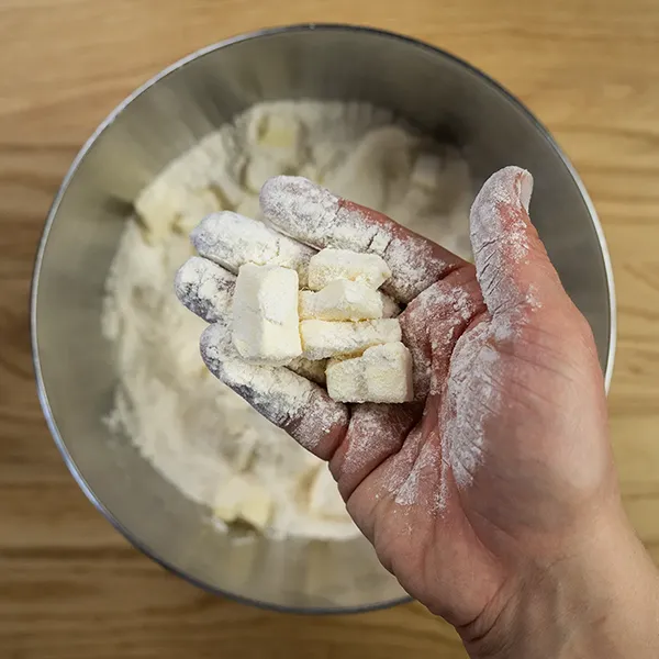 Tossing butter cubes in flour to coat.