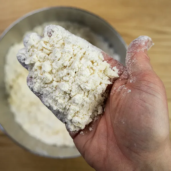 Cutting butter into flour until no larger than the size of peas.