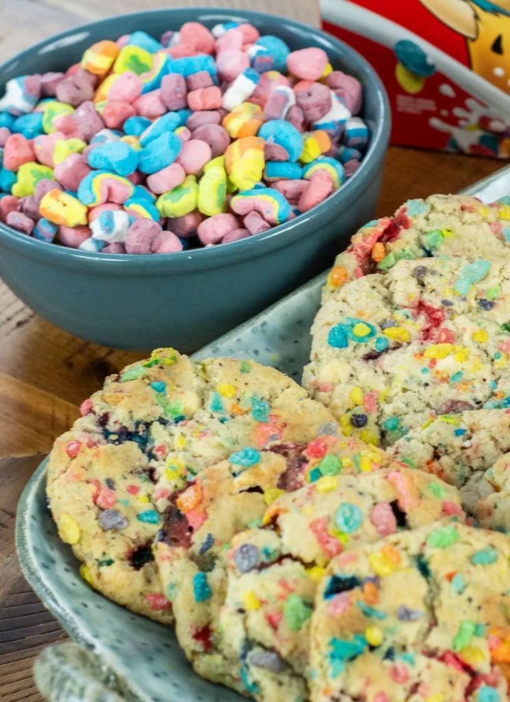 Lucky Charms cookies with Fruity Pebbles, with a bowl of Lucky Charms marshmallows in the background.