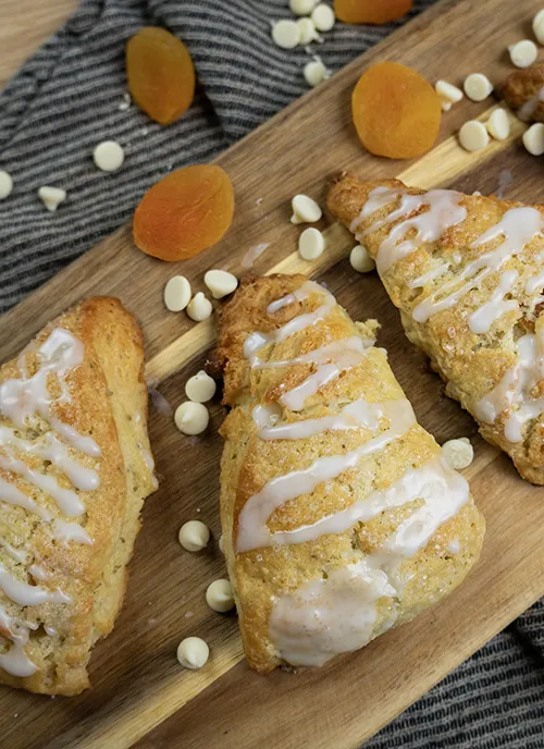 Sourdough apricot & white chocolate scones on a wooden board.