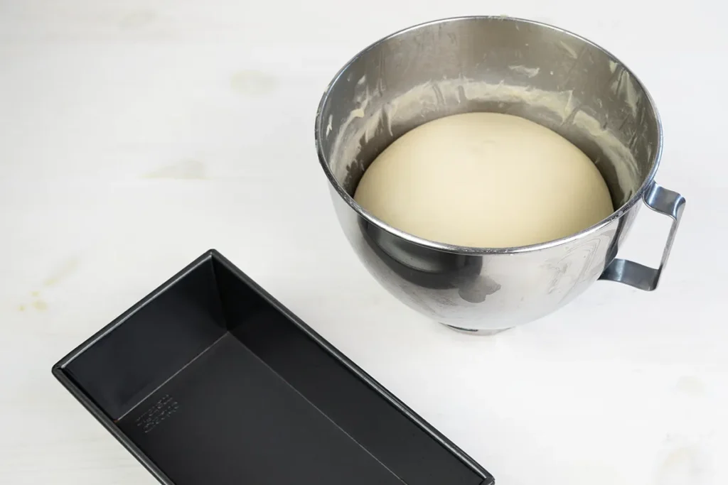 Fully-proofed sourdough sandwich bread dough in a mixing bowl ready to be shaped.