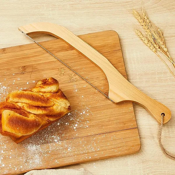 A bow-style sourdough bread knife on a wooden cutting board.
