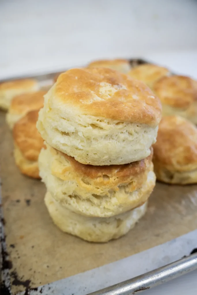 Sourdough biscuits piled on a baking sheet.