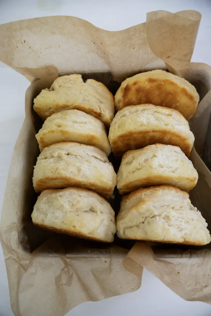 Row of sourdough biscuits in a metal baking pan lined with parchment paper.