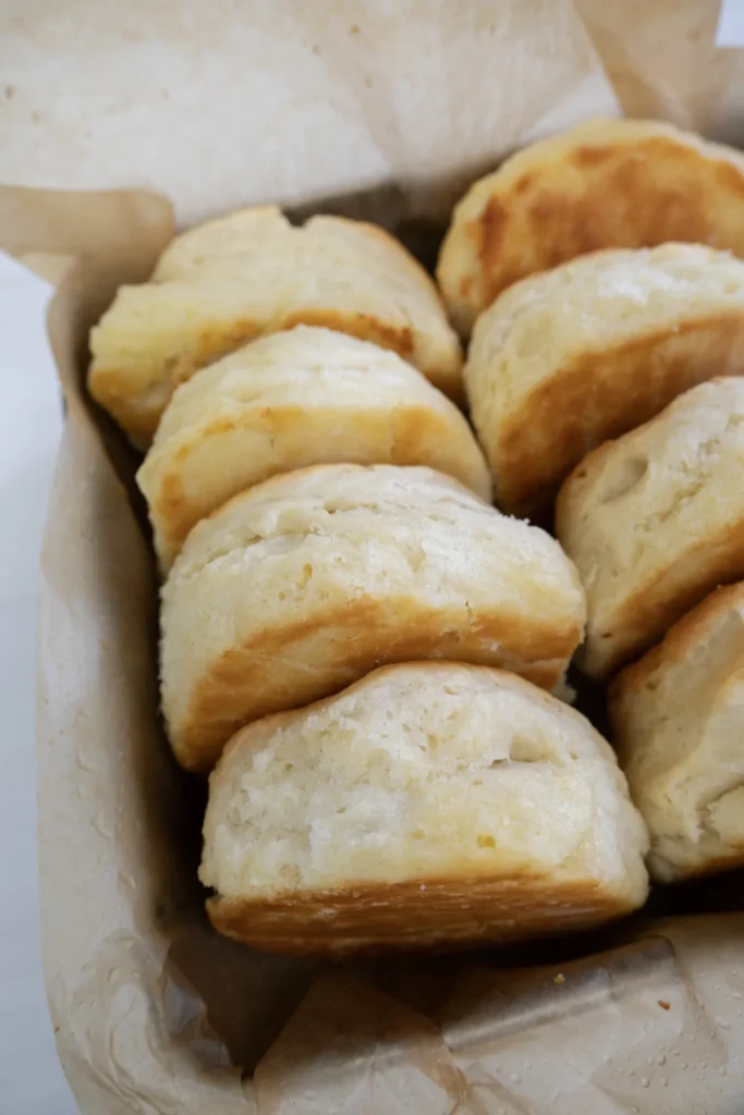 Row of sourdough biscuits in a metal baking pan lined with parchment paper.