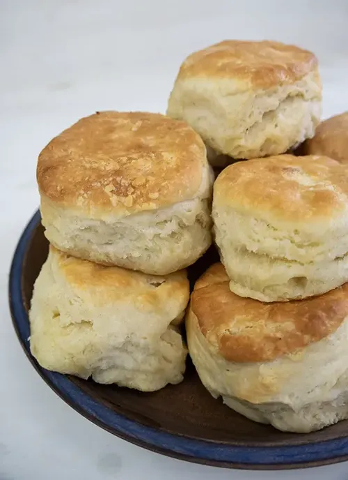 A stack of sourdough biscuits on a wooden plate.