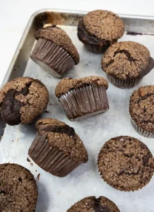 Sourdough double chocolate banana muffins scattered on a baking sheet.