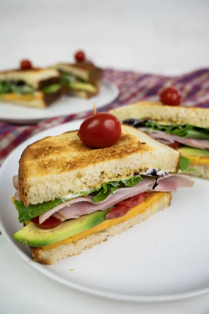 Ham, veggie, and cheese sandwiches made with sourdough sandwich bread.