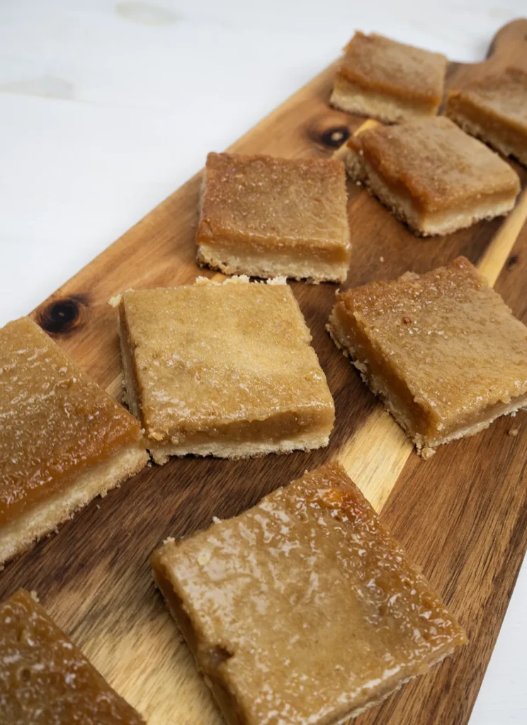 Butter tart squares arranged on a wooden board.
