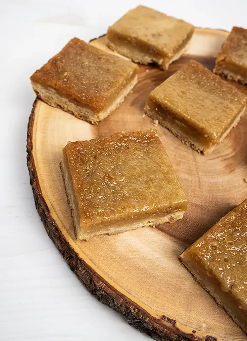 Butter tart squares arranged on a wooden plate.