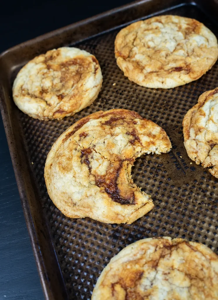 Sourdough gochujang caramel cookies on a baking sheet. One cookie has a bite taken out of it.