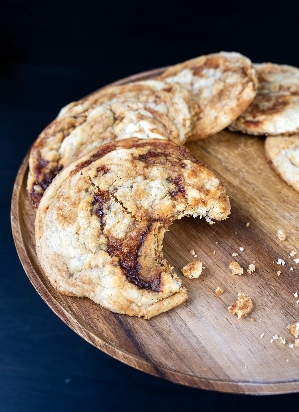 Sourdough gochujang caramel cookies on a wooden cake stand. One cookie has a bite taken out of it.
