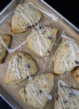 Top-down view of glazed sourdough discard scones with cranberry and white chocolate, arranged on a baking sheet.
