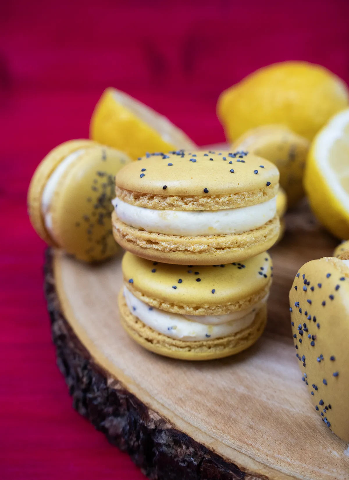 Lemon poppyseed macarons stacked on a wooden platter.