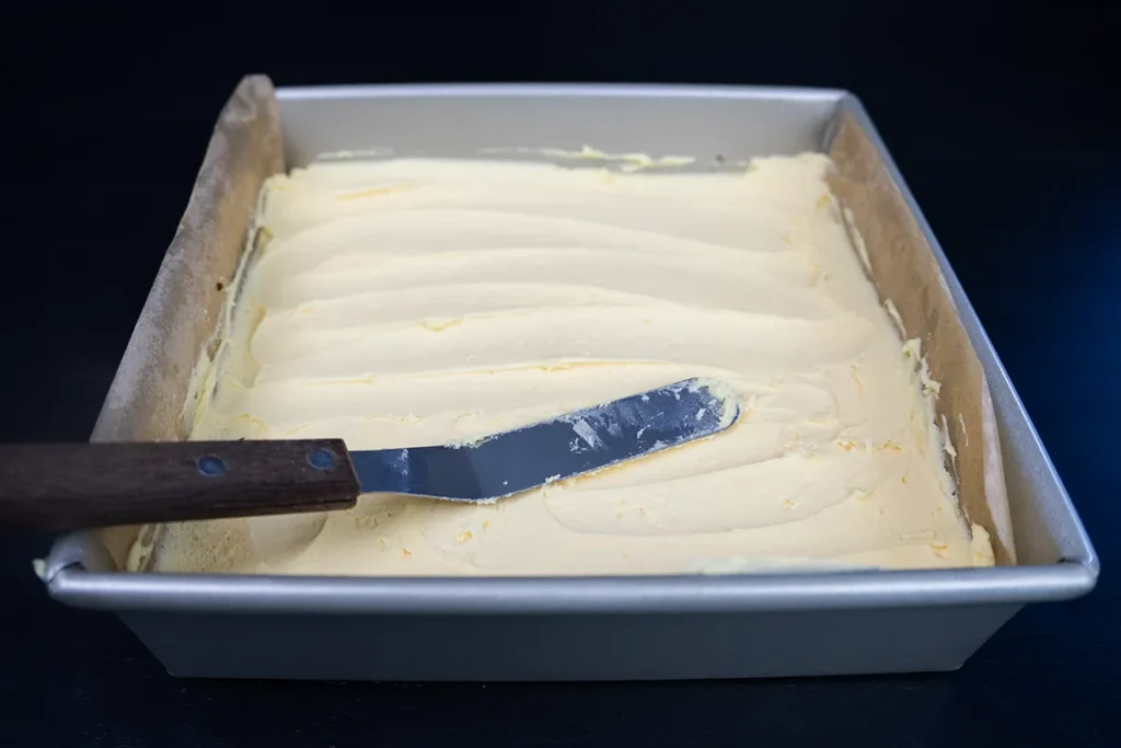 The middle (custard-flavoured buttercream) layer of a Nanaimo bar, in a square pan.