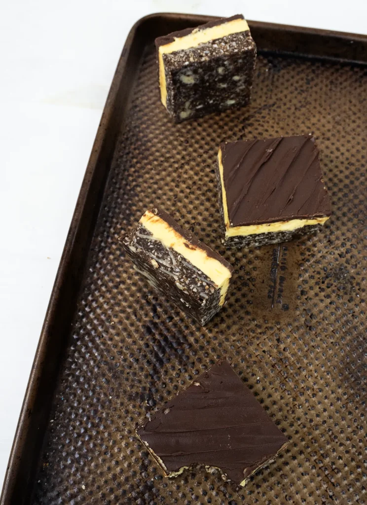 Nanaimo bars scattered over a baking sheet.