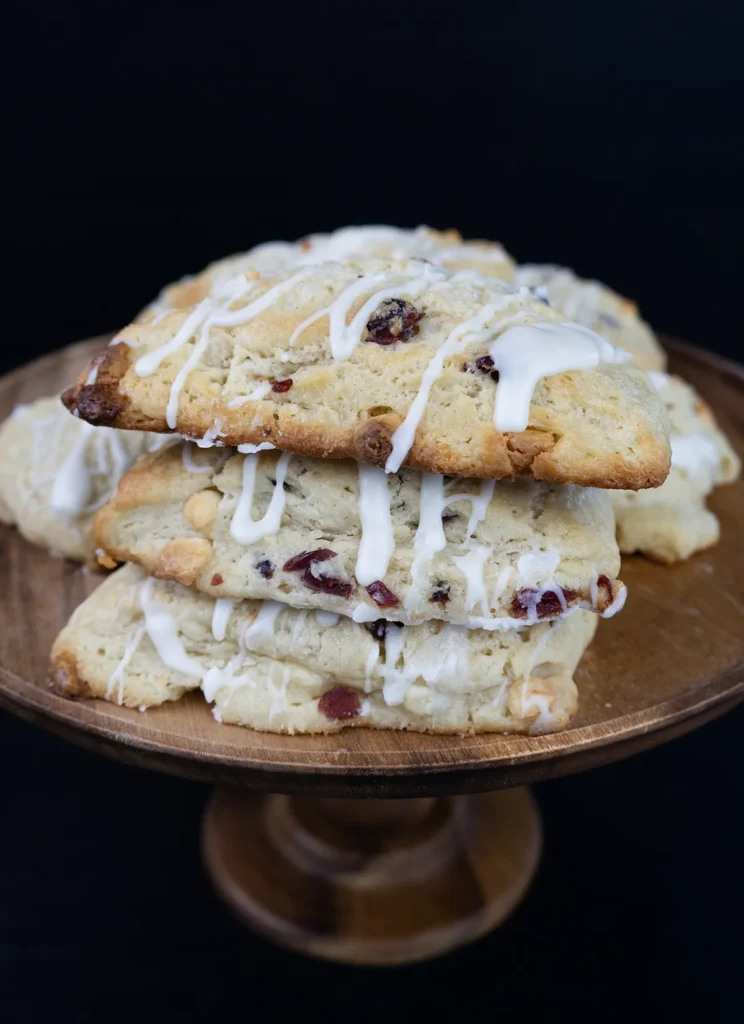 Stack of glazed scones on a wooden cake stand.