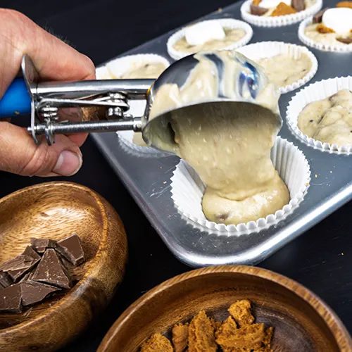 Filling a muffin cup with sourdough banana s'mores batter.