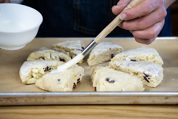 Brushing scones with heavy cream.