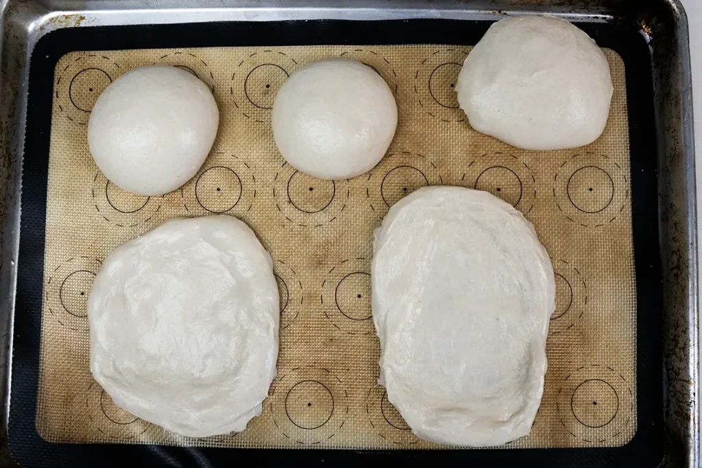 Sourdough Beaver Tail dough shaped into flat ovals, ready to be deep fried.