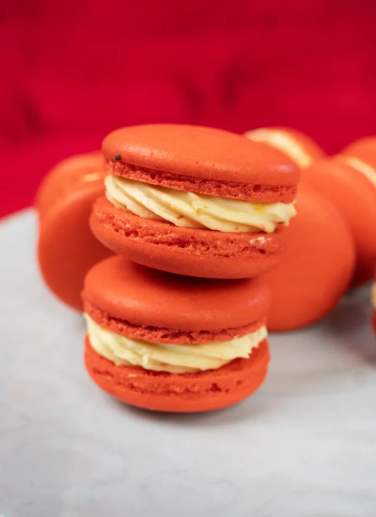Strawberry Mango Tajín macarons scattered on a plate.