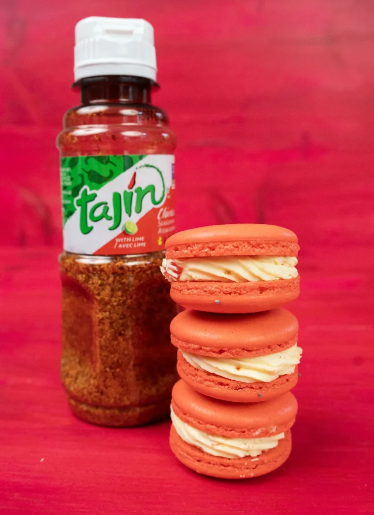 Strawberry Mango Tajín macarons stacked next to a bottle of Tajín.