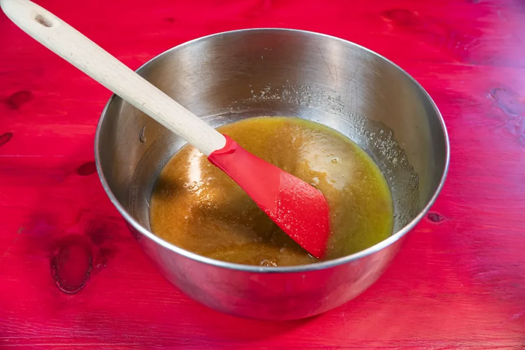 Mixing melted butter, brown, and white sugar to make Cookie Monster cookies.