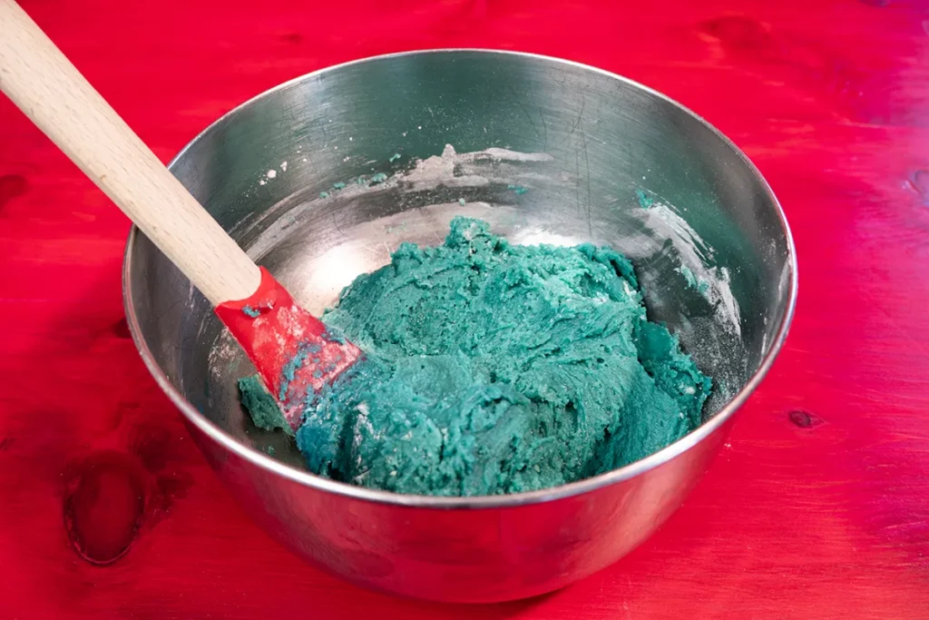 Adding dry ingredients to cookie monster cookie dough and mixing just until combined.