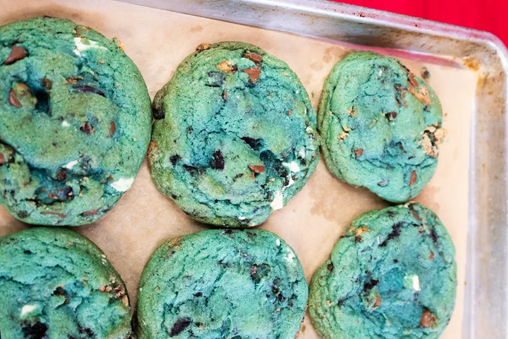 Baked blue cookie monster cookies on a lined baking sheet.