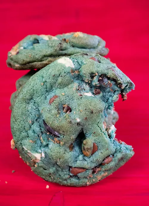 A stack of blue cookie monster cookies. One cookie has a bite taken out of it.