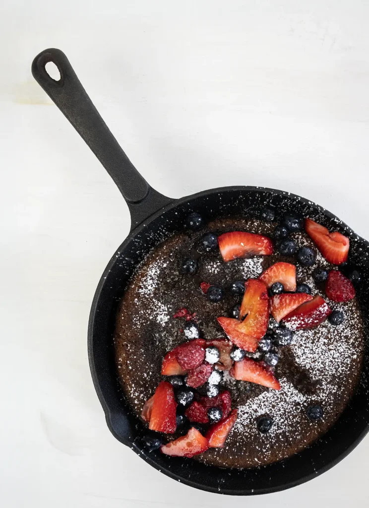 Overhead view of a giant skillet pancake topped with fresh fruit.