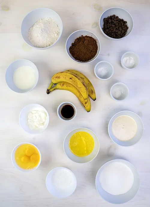 Overhead shot of a variety of baking ingredients, including eggs, butter, bananas, cocoa powder, and more.