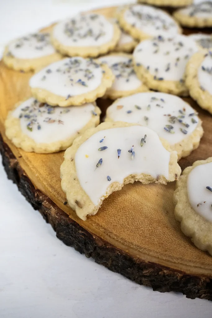 Glazed lemon lavender shortbread cookies arranged on a wooden plate.